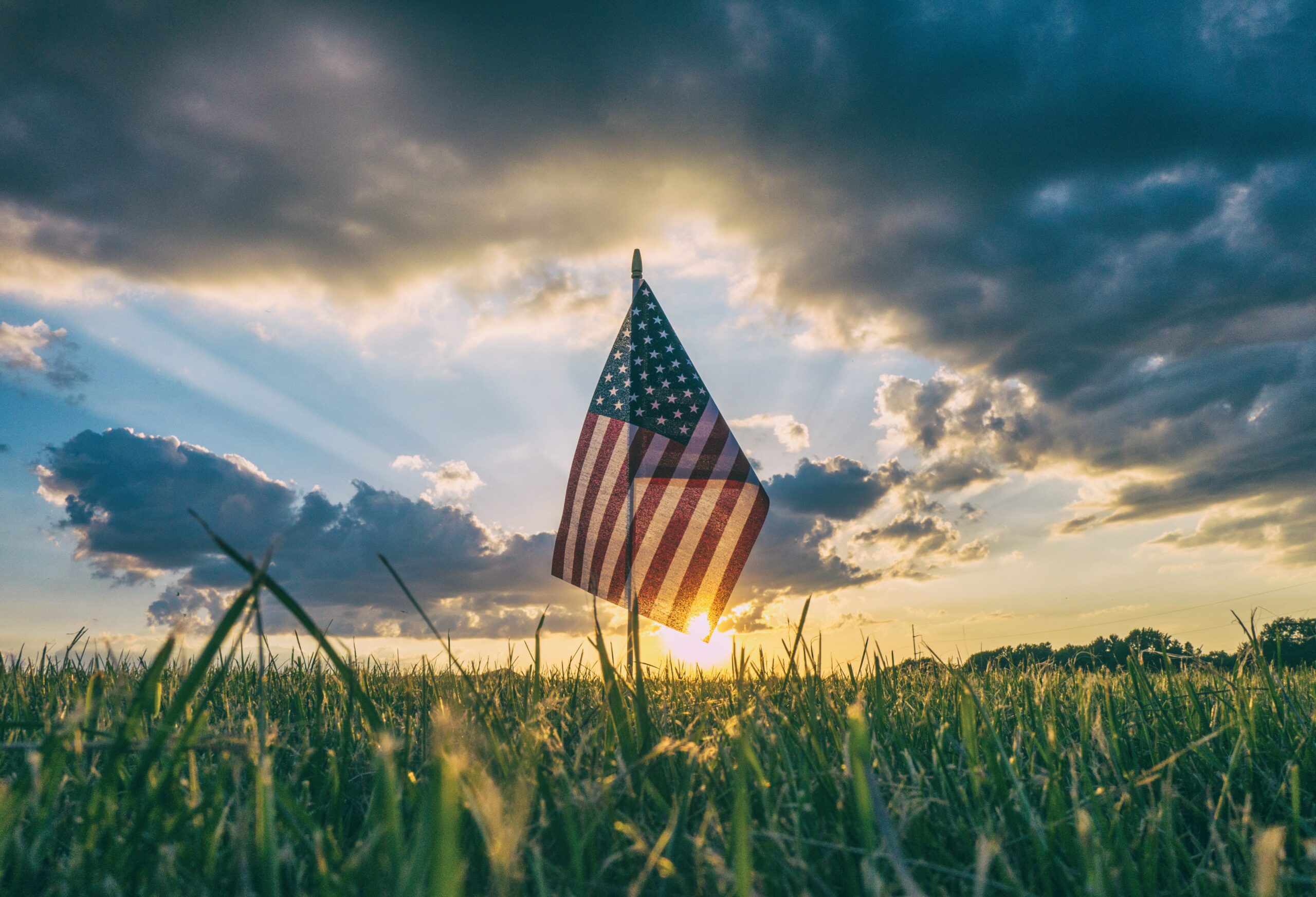 An American flag in front of a sunset.